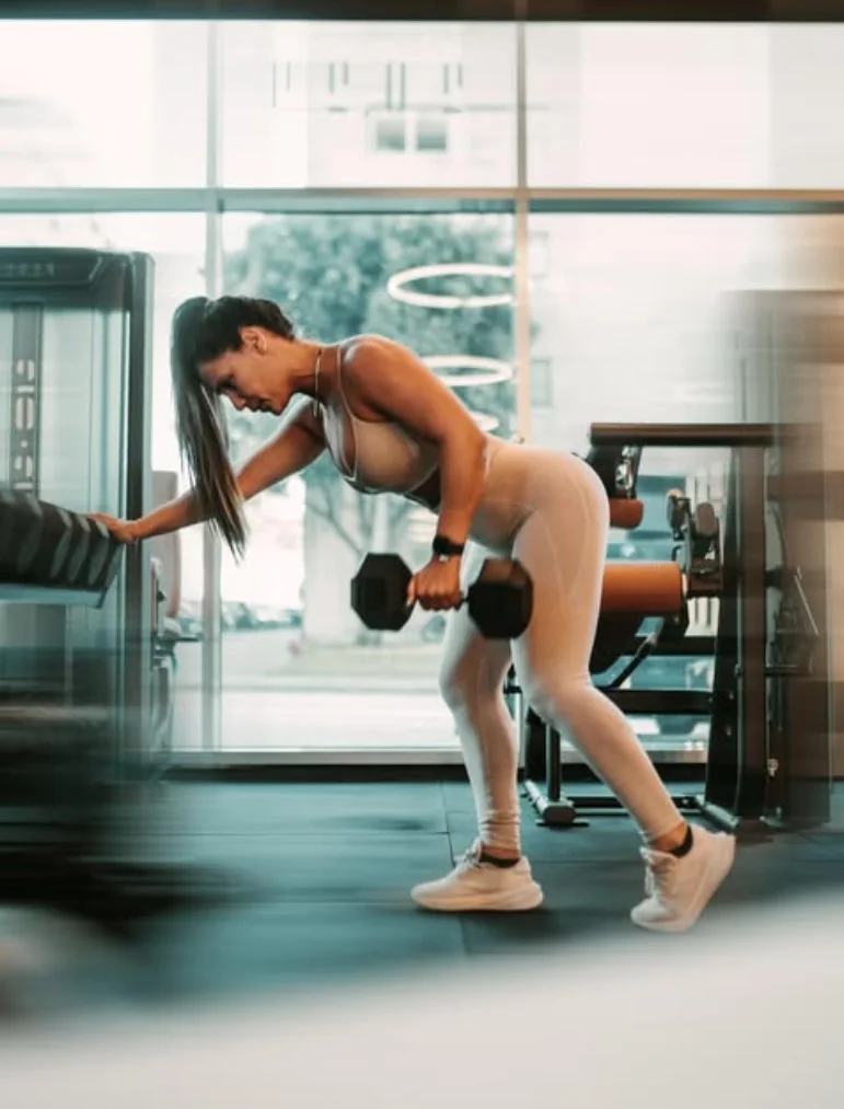 Treinadora a fazer remo com halter junto a uma janela